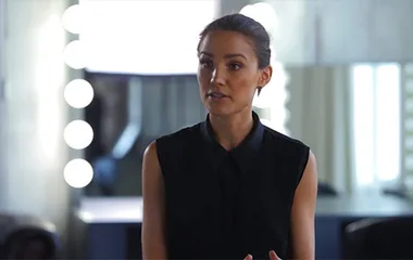 Person speaking in a dressing room with round lights in the background.