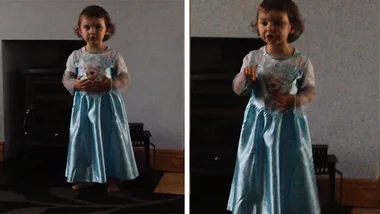 A little girl in an Elsa dress from Frozen stands and gestures passionately.