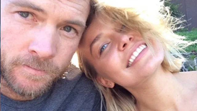 Two people smiling closely in a selfie, one with blonde hair, outdoors.
