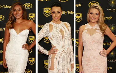 Three women pose on the red carpet at the Dally M Awards 2014, wearing elegant white and blush-colored gowns.