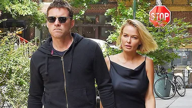 Couple walking in West Hollywood, with greenery and a stop sign in the background.