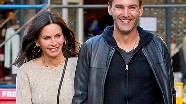 A woman and a man walking together, both smiling and casually dressed.