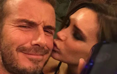 Victoria kisses David Beckham on the cheek, both posing closely for a selfie.