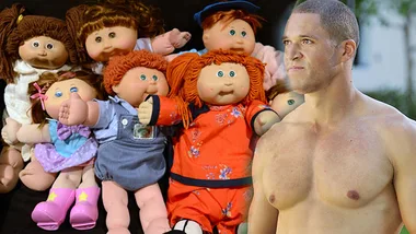 A shirtless man stands beside a group of Cabbage Patch dolls dressed in colorful outfits.