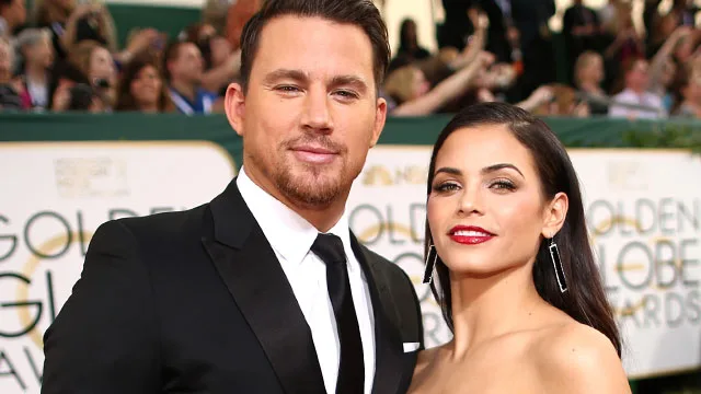 Man in a suit and woman in a strapless dress pose at an award event with Golden Globes signage in the background.