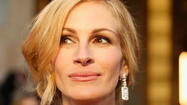 Julia Roberts with an elegant updo and diamond earrings at a formal event, highlighting natural beauty and grace.