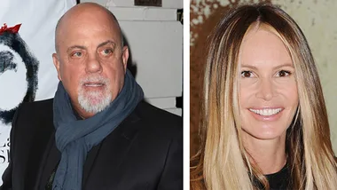Billy Joel in a scarf and jacket next to a woman with straight hair smiling at an event.