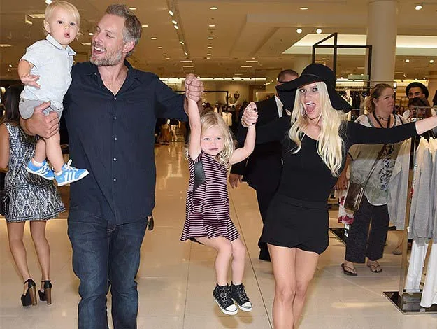 A cheerful family enjoying a fun moment in a store, with the parents holding up two young children playfully.