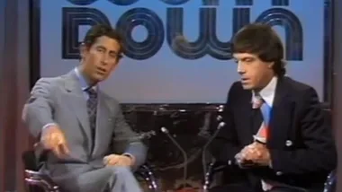 Prince Charles and Molly Meldrum seated on "Countdown" set, engaging in conversation, wearing suits.
