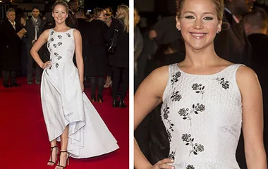 Jennifer Lawrence in a white floral dress at The Hunger Games premiere, posing on the red carpet with a smile.