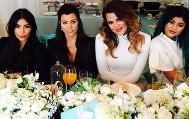 Women seated at a elegantly decorated table with flowers and gifts at a "Breakfast at Tiffany's" themed event.
