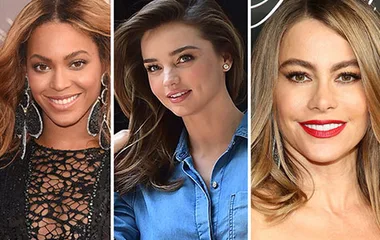Three women smiling at an event, each with styled hair and elegant outfits.