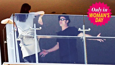 Two individuals engaged in a discussion on a balcony, featured in Woman's Day.