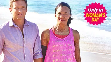 Two people standing on a beach, one with visible burns, smiling. "Only in Woman's Day" logo in the corner.