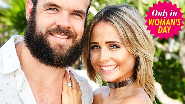 Couple smiling outdoors, man with beard, woman with blonde hair; Woman's Day badge on top right.