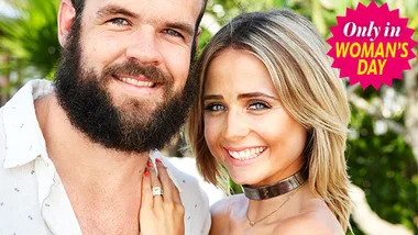Couple smiling outdoors, man with beard, woman with blonde hair; Woman's Day badge on top right.