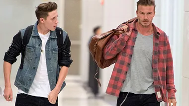 Two men walking, one with a checked shirt carrying a bag, the other in a denim jacket, in a brightly lit hallway.