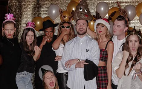 Group photo at a festive birthday party with balloons, wearing novelty hats and accessories, posing playfully.
