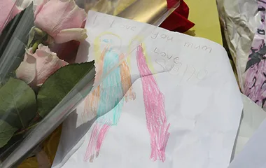 A child's drawing with the message "Love you mum" among flowers laid as a tribute.