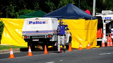 Police scene with officers, tents, and vehicles at crime site in Cairns.