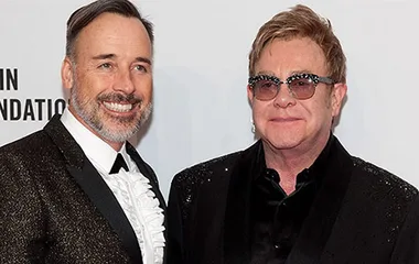 Two men in formal attire smiling at a formal event backdrop.