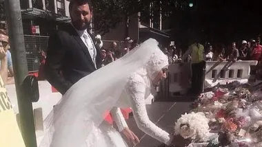 Bride in white gown and veil lays flowers at Martin Place memorial, surrounded by onlookers and flower tributes.