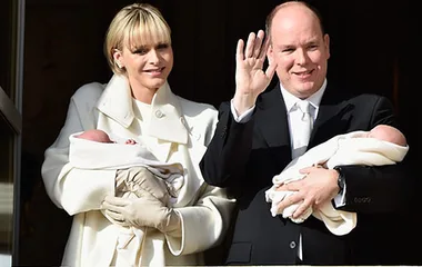 Princess Charlene and Prince Albert of Monaco present their newborn twins, each holding a baby, on a balcony.