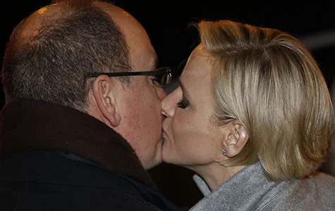 Couple sharing a tender kiss outdoors at night, dressed in winter clothing.