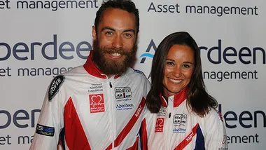 Two people smiling, wearing racing jackets, standing in front of a backdrop with "Aberdeen Asset Management" logos.
