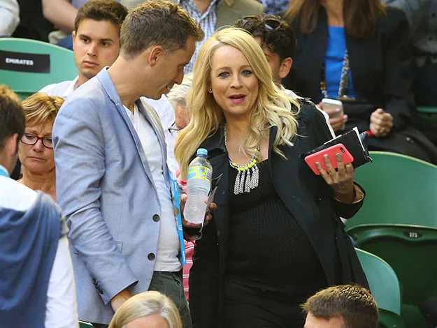 Couple in a crowded stadium, woman holding water bottle and phone, man listening closely.