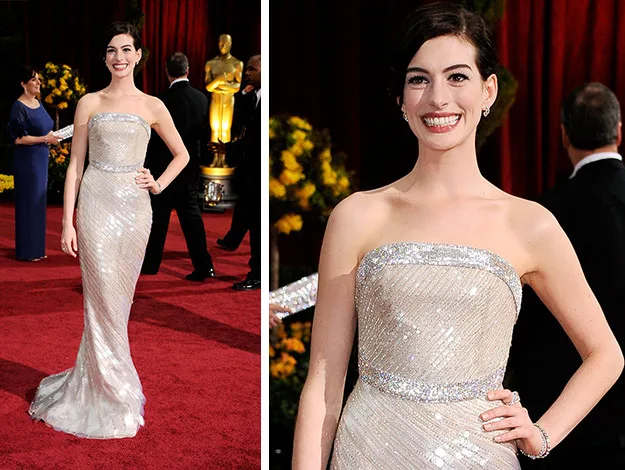 Smiling woman in a strapless silver gown poses on the red carpet at a formal event.