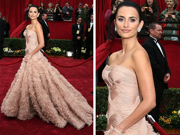 Person in an elegant, strapless, nude-colored gown on a red carpet, with photographers in the background.