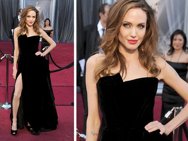 Celebrity in a black strapless dress with a thigh-high slit, posing on a red carpet event.