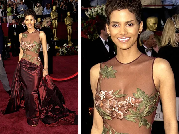 Woman in a sheer floral gown with brown satin skirt on the red carpet, surrounded by people and Oscar statues.