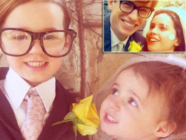 Two young children dressed as characters from "The Theory of Everything" with a yellow rose and grown-up photo inset above.
