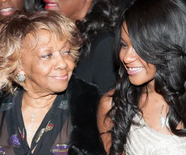 An older woman and a younger woman smiling at each other warmly at a public event.