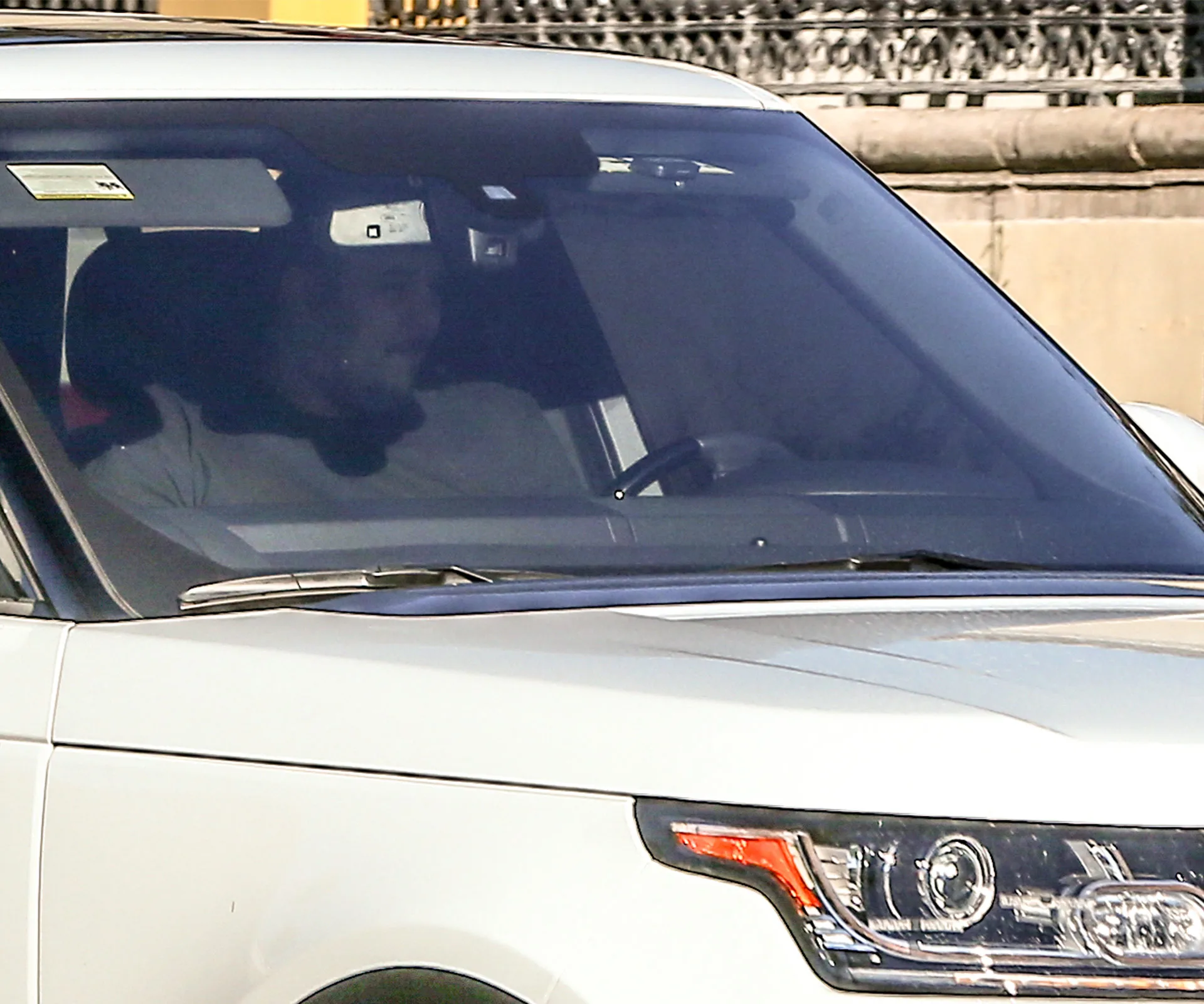 A person driving a white SUV on a sunny day, partially visible through the windshield.