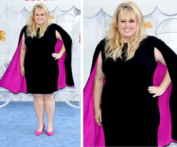 "Person in black dress with pink cape at MTV Movie Awards red carpet."