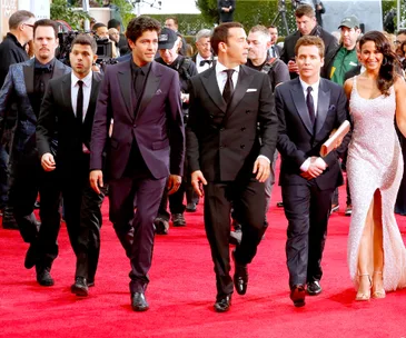 Cast of "Entourage" on a red carpet, dressed in formal attire, with photographers in the background.