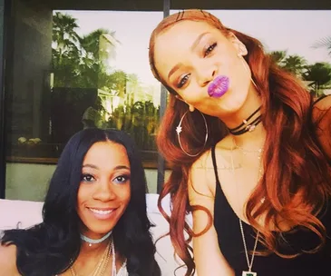 Two women taking a selfie outdoors, one with purple lipstick, smiling at the camera.