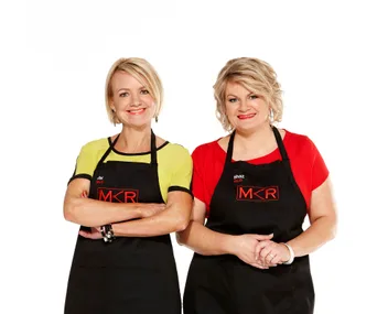 Two women in "MKR" aprons smiling and standing together against a white background.