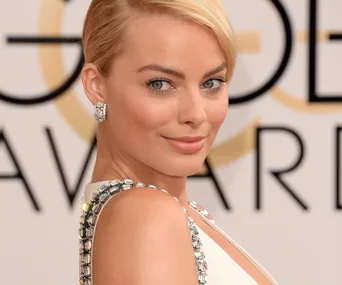 Actor in an elegant dress with jeweled straps, smiling at an event.