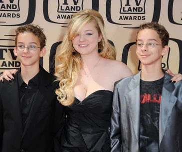 Three young individuals smiling at the TV Land Awards, dressed in formal attire.