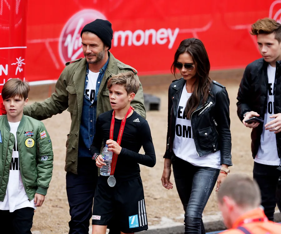 Family cheering on their son at the London Marathon, son wears a medal.