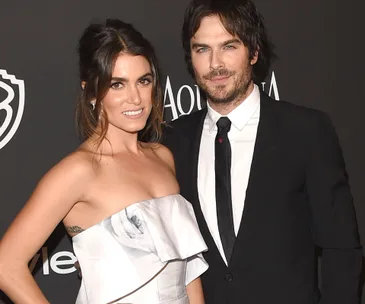Couple smiling at event, wearing formal attire, posing together.