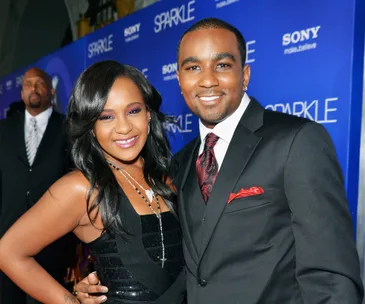 A couple smiling at a "Sparkle" movie premiere event with a blue backdrop.