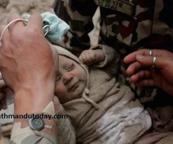 Rescuer cradles a small, dusty baby in their arms after being pulled from rubble in Nepal.