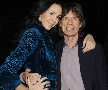 Two people posing closely together, one in a blue velvet jacket, smiling.