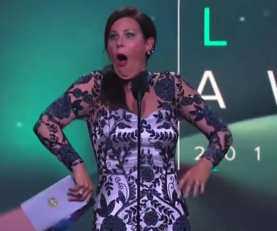 Julia Morris on stage at the Logies, wearing a lace dress, making a surprised expression.