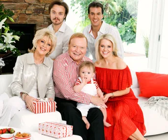 A family gathered on a white couch, wearing coordinating red and white outfits, with gifts and smiling expressions.